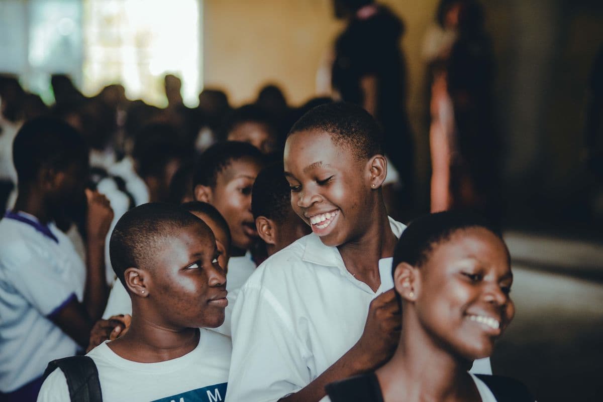 Teenagers in school uniform smiling together indoors