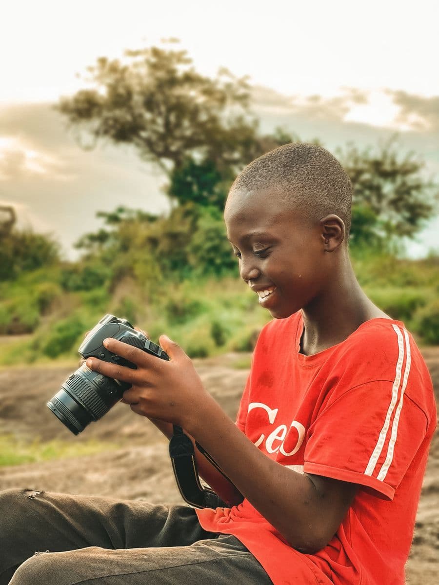 A smiling young person reviewing a photograph on a camera screen